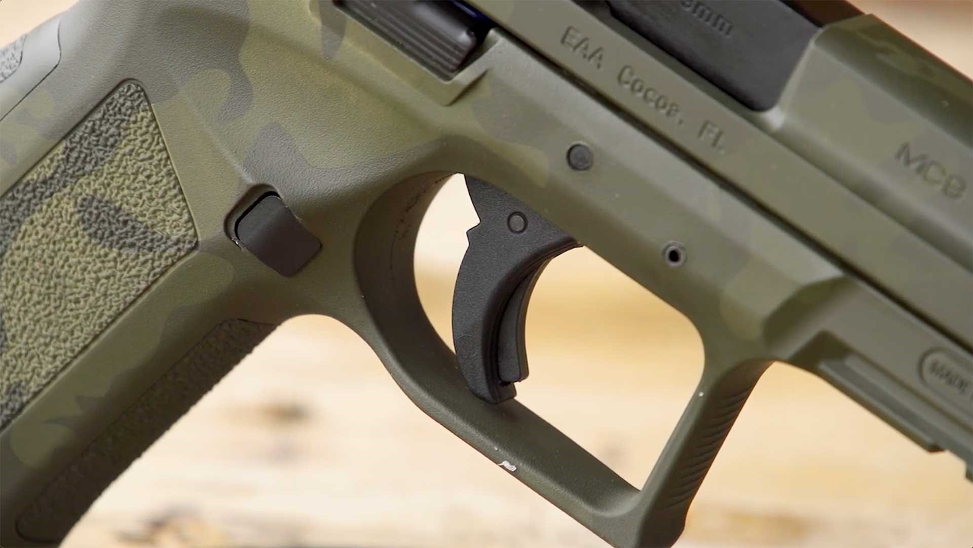 A black trigger blade sits inside the trigger guard of the camouflage-finished EAA Girsan MC9 Disruptor.