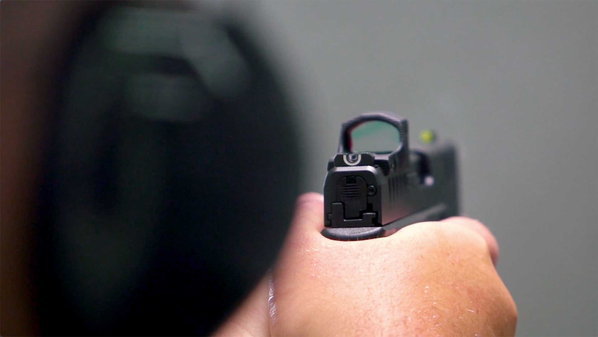 Man aims Springfield Armory Hellcat Pro pistol toward a target.