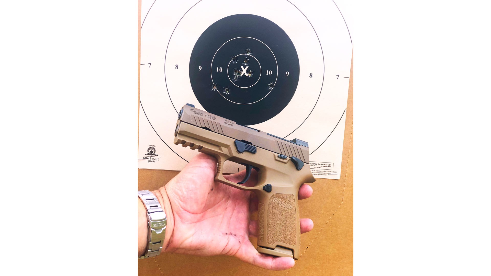 SIG Sauer M18 in hand next to target bullseye