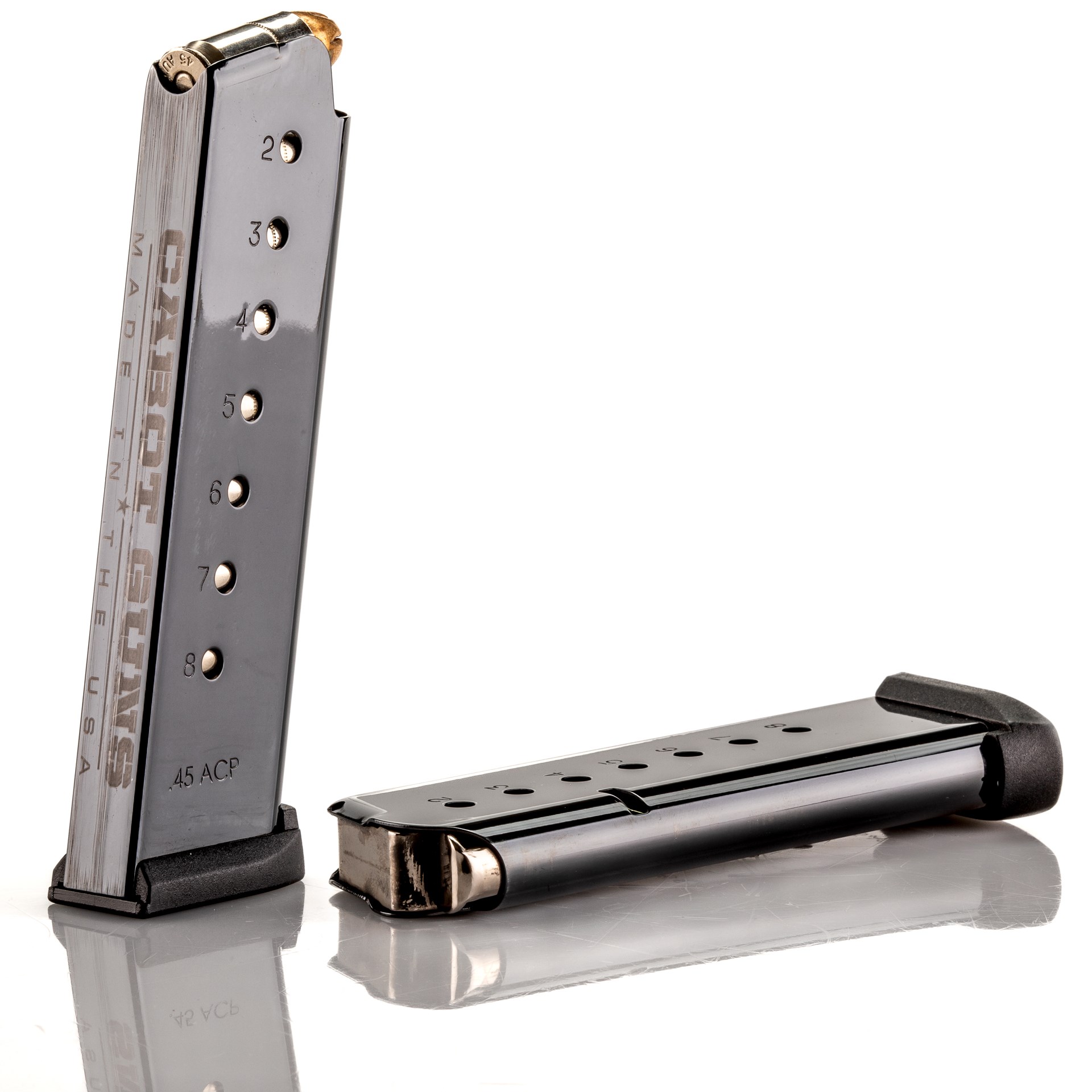 cabot guns southpaw m1911 pistol magazine ammunition vertical standing black steel horizontal laying down on white reflection on white table mirror-like appearance