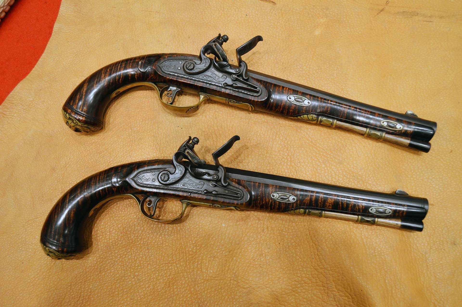 Two flintlock pistols shown on a deerskin background.