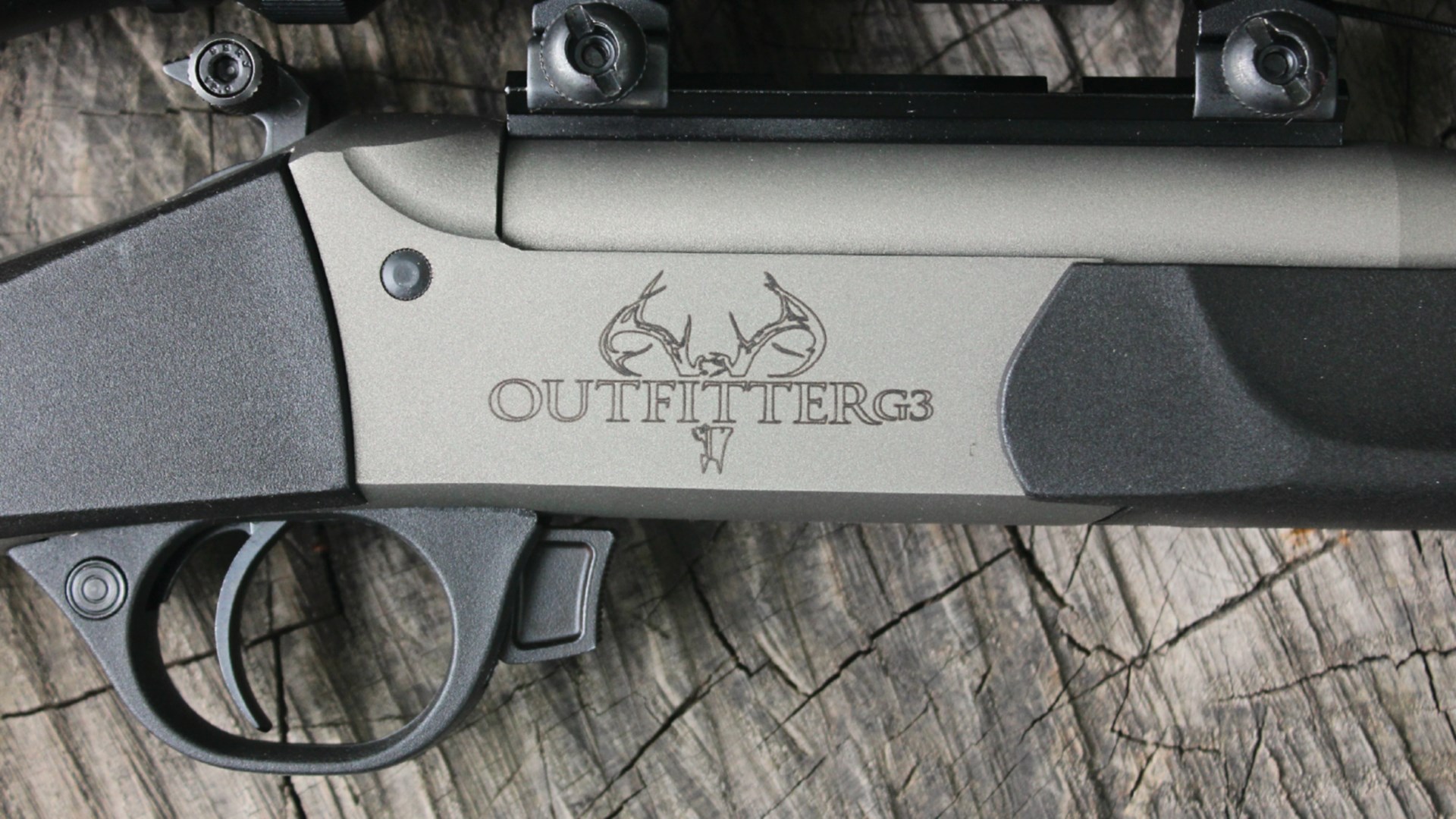 Traditions Outfitter G3 single-shot rifle .300 BLK black plastic stock cerakote silver colored barreled action closeup showing right-side markings deer skull engraving text
