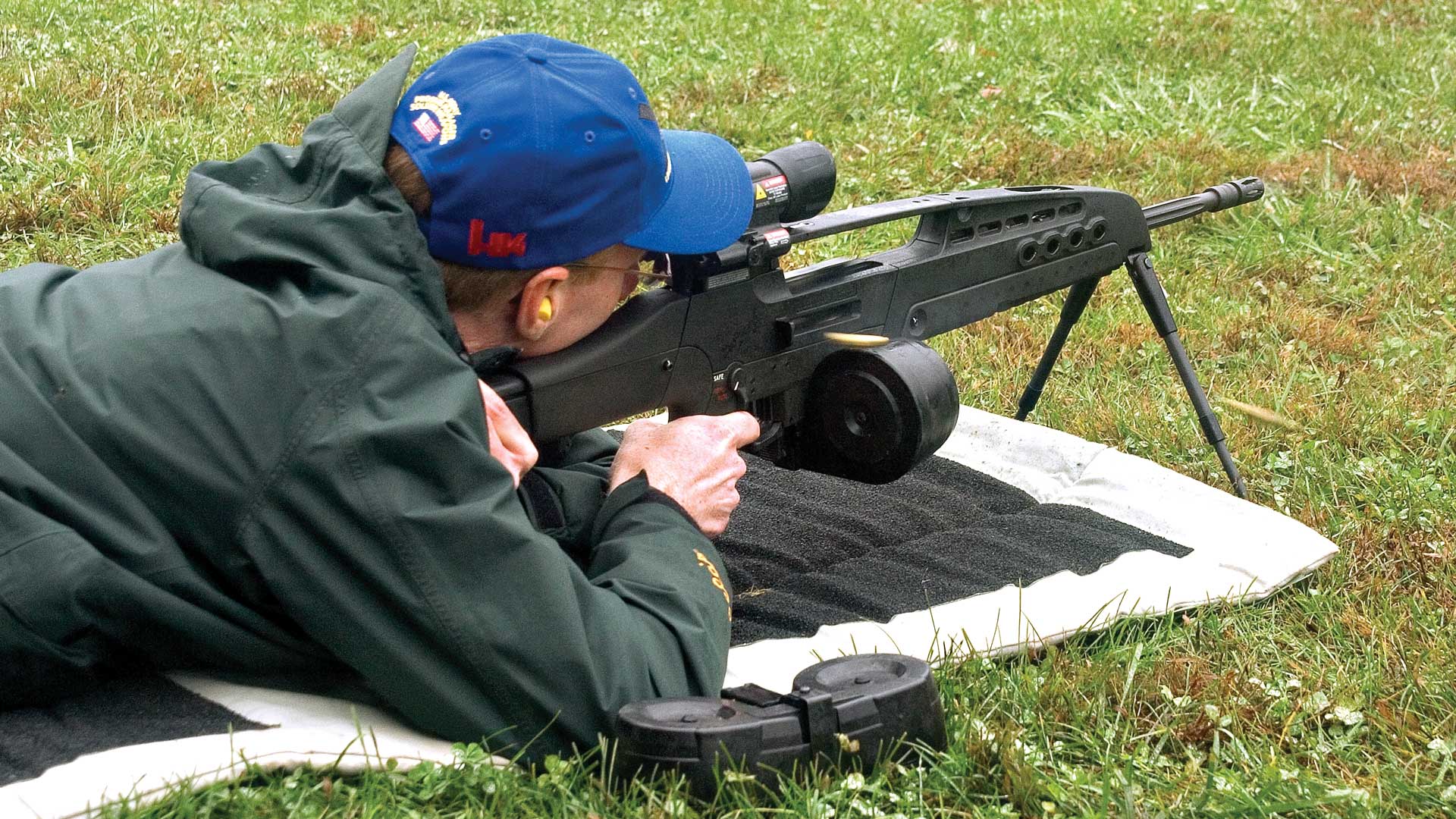 outdoors man blue hat shooting ground grass mat rifle xm8 gun