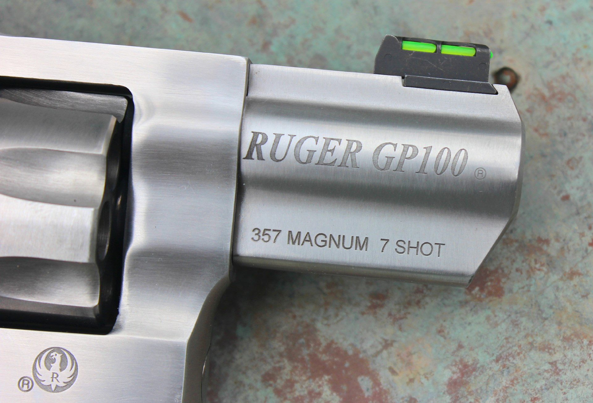 Ruger GP-100 7-shot revolver barrel closeup marking stamping gun barrel details logo text stainless steel fiber-optic sight revolver cylinder crop