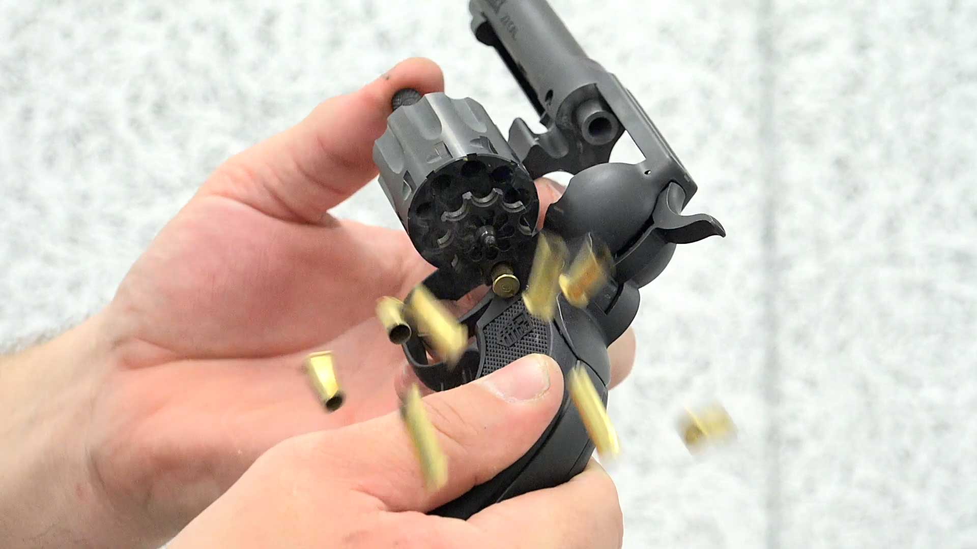 hands holding black revolver brass case ejection cartridges gun empty