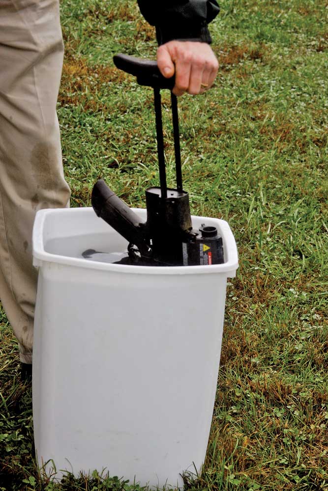 white bucket dunk water gun rifle testing outdoors grass man kaki pants