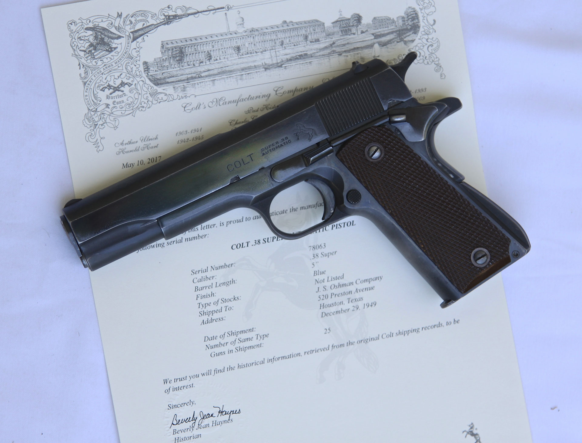 Fat barreled Colt .38 Super semi-automatic pistol, blued metal and dark wood grips, on top of a white background and a Colt factory letter.
