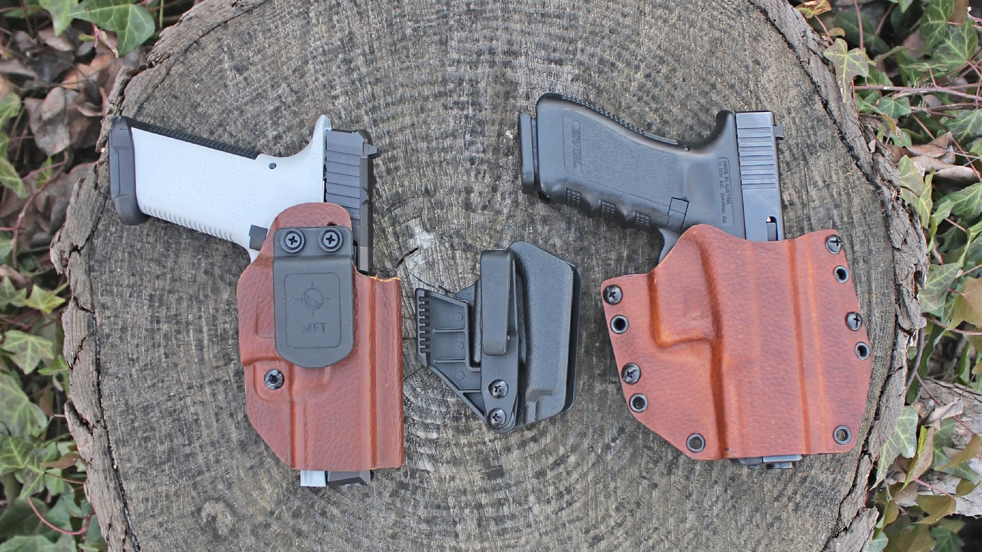 Mission First Tactical holsters and guns two pistols on log leaves outdoors