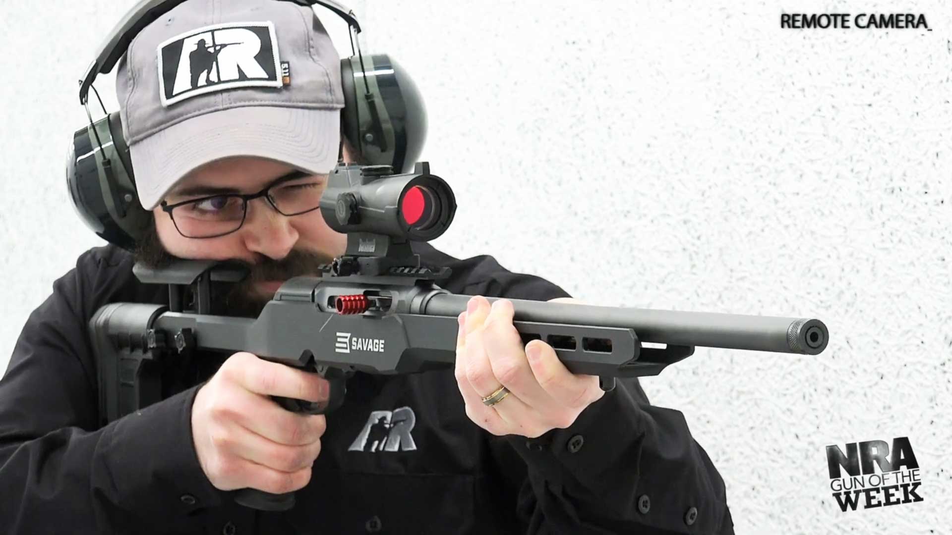 Man wearing black shirt ballcap earmuffs protective gear shooting rifle firearm gun target semi-automatic Savage Arms A22 Precision