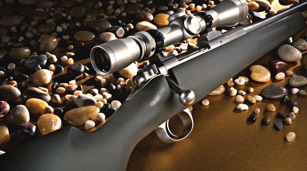 Kimber America 84M Montana rifle bolt-action stainless steel on table with stones pebbles rocks