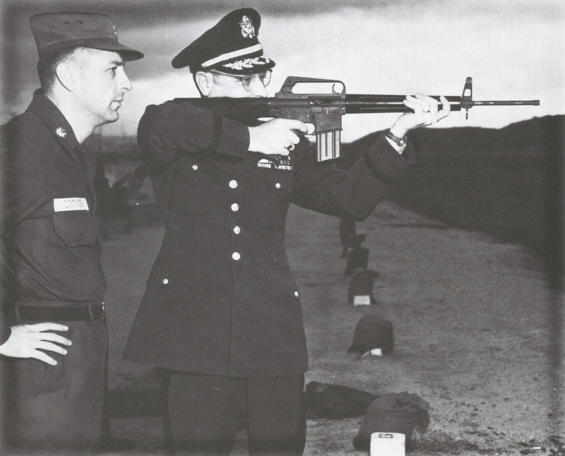 Major Eugene M. Lynch observes Lt. Col. Robert Vallendorf as he shoulders an ArmaLite prototype AR-15 (possibly S/N 000013) at Fort Benning on March 31, 1958. The rifle has no flash suppressor, but it is equipped with the AR-10 trigger type charging handle, one-piece cylindrical fiberglass handguard, and 25-round capacity magazine. U.S. Army photo