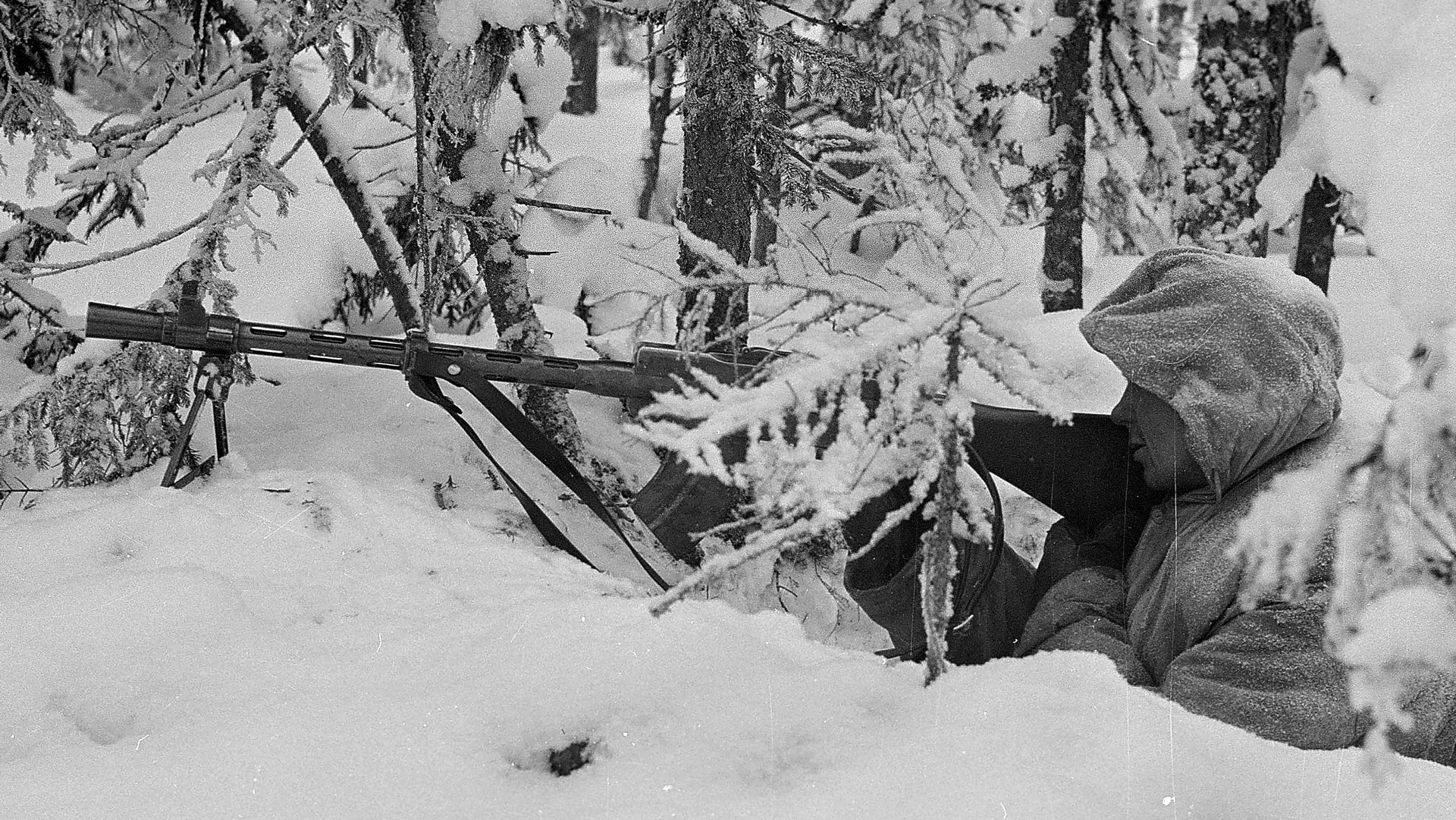 Finnish light machine gun shown left-side view hidden by snow-covered trees soldier