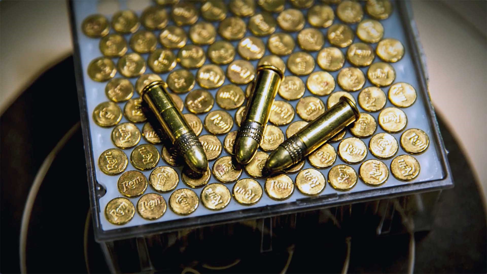 Three .22 Long Rifle cartridges sitting on top of a box of Remington .22 LR shells.
