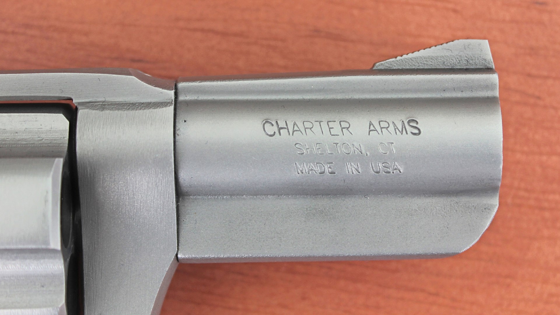 Charter Arms bulldog barrel revolver front sight stainless steel closeup muzzle wood table background