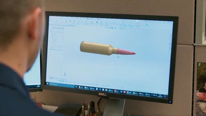 Man looking at computer screen with ammunition design software on screen.