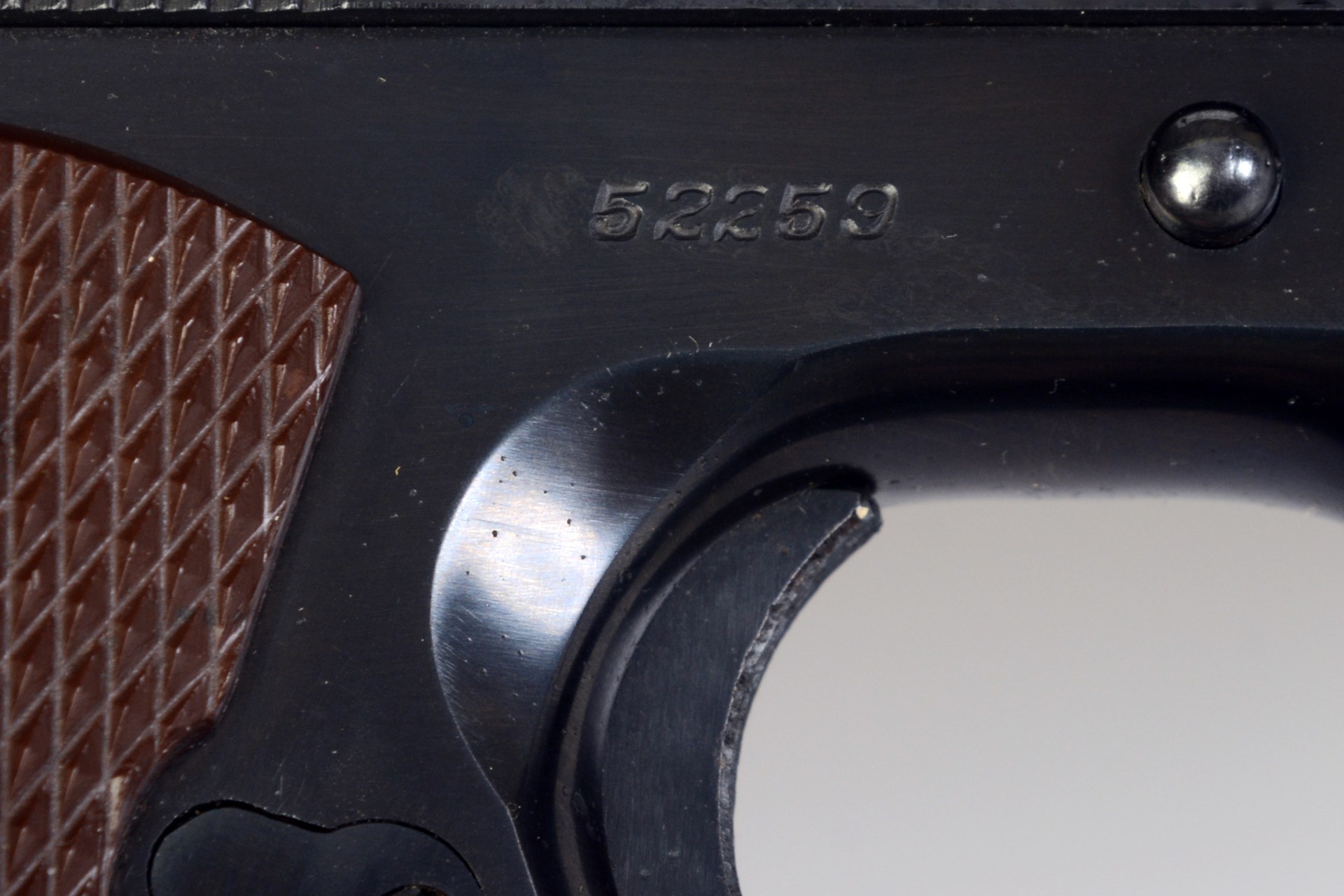 closeup of serial number stamping in colt 1911 metal pistol frame above trigger