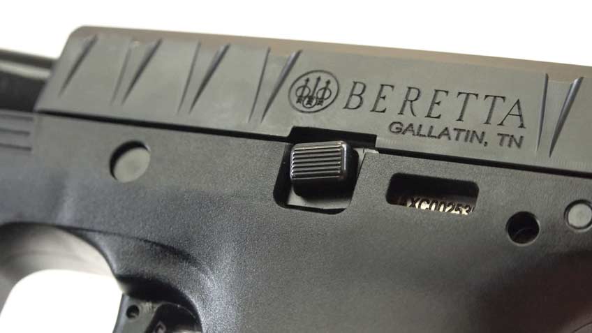 Closeup of black pistol with engraving noting Beretta brand with logo