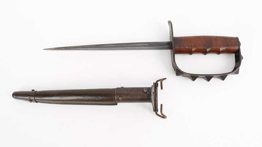 Fighting knife with handguard attached shown on white background with sheath.