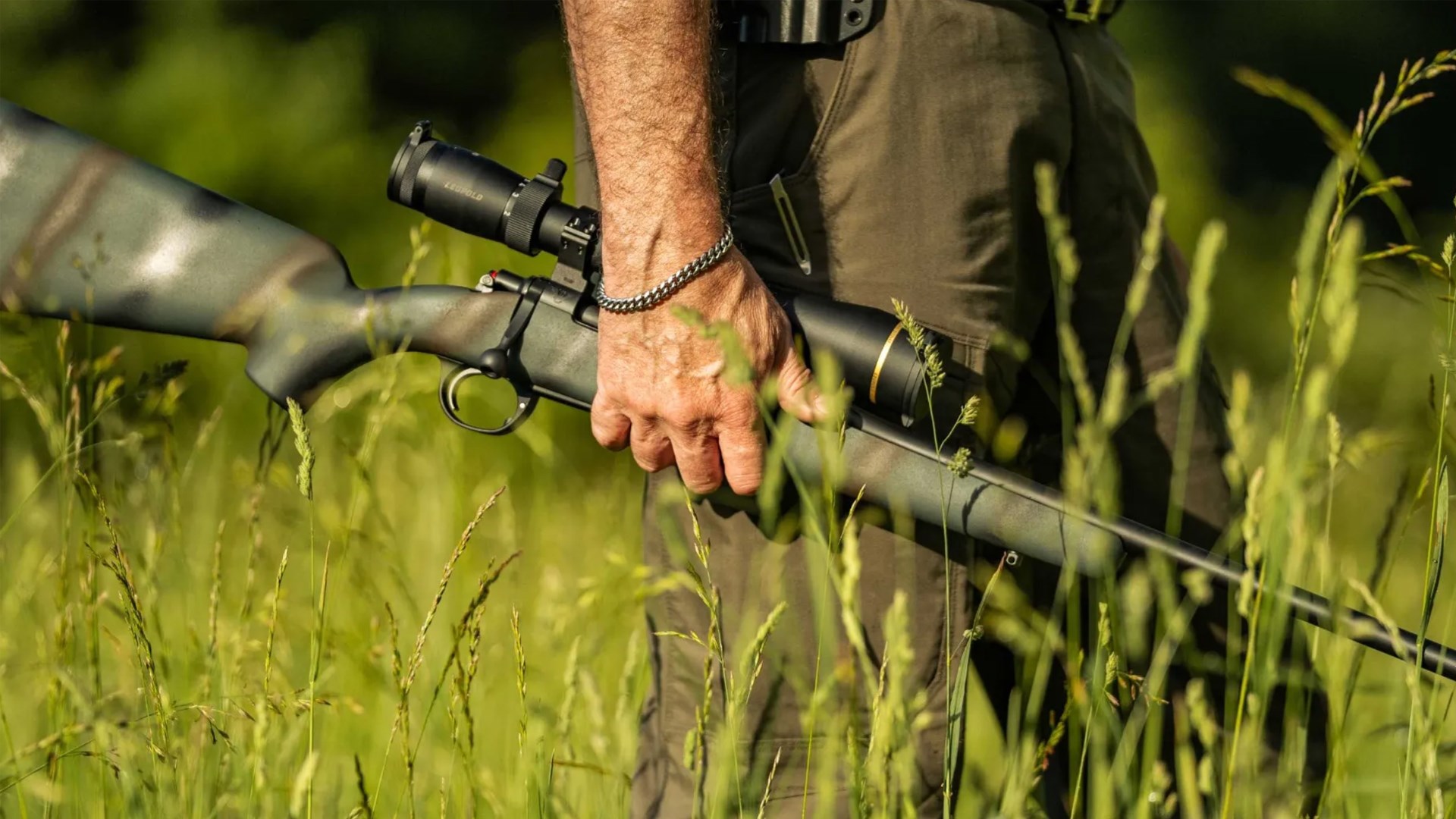 Man carrying the Wilson Combat NULA Model 20 rifle in an open field.