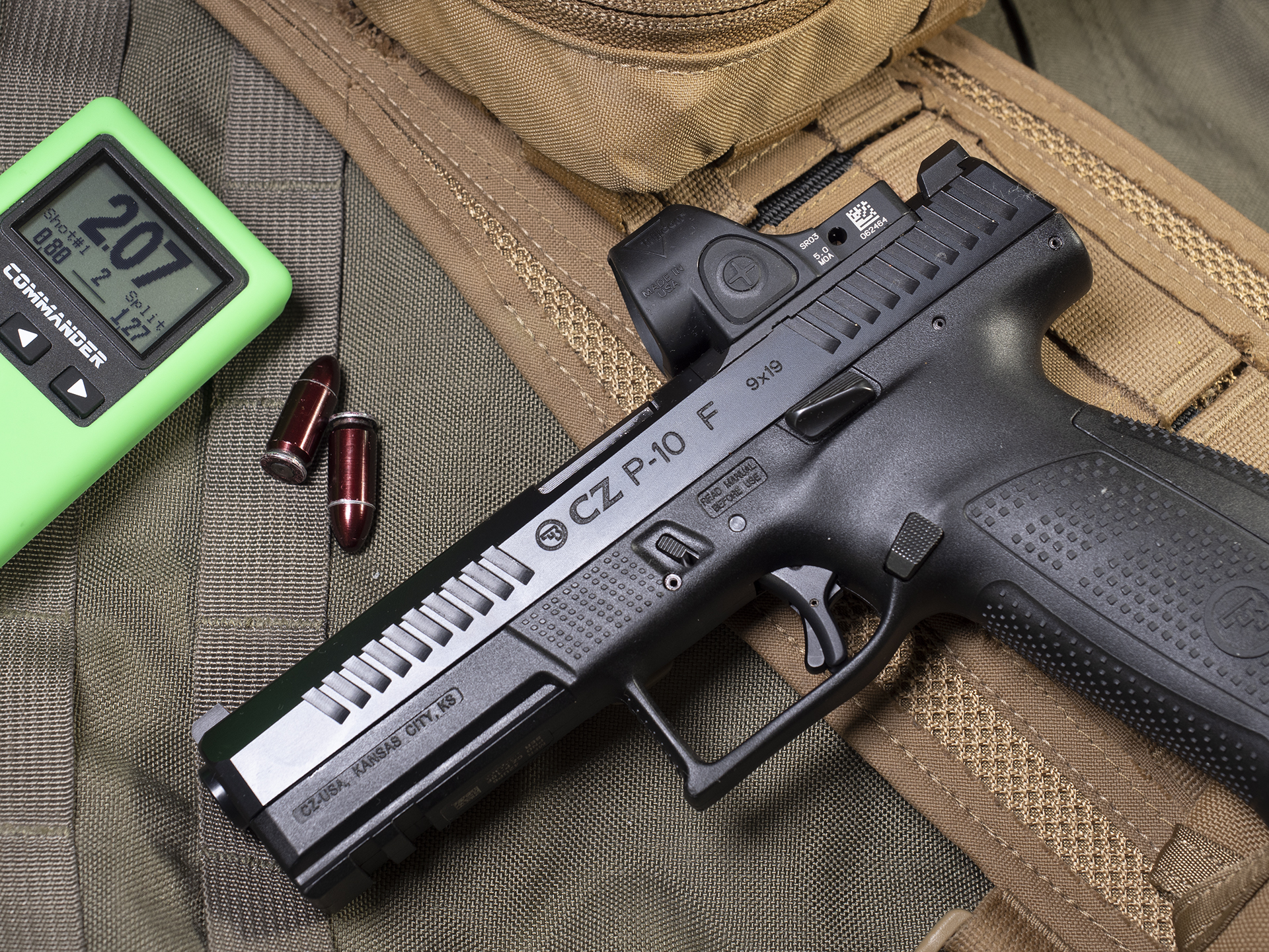 CZ P-10C with two 9 mm dummy round and a shot timer on top of green and tan gear.
