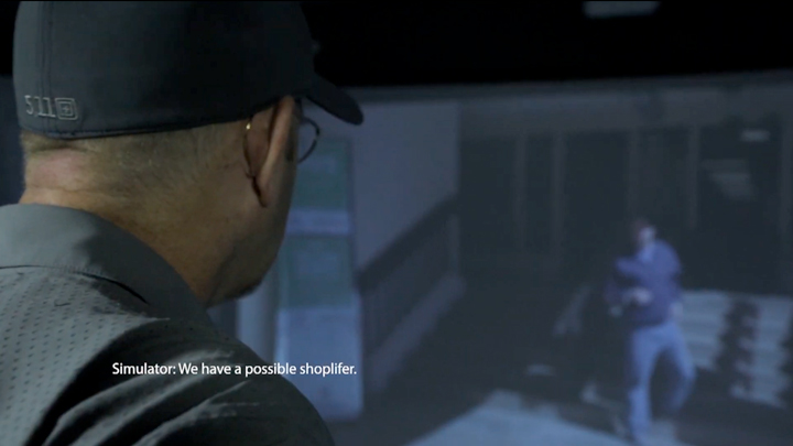 Man with ballcap in front of screen simulation with text on image stating &quot;Simulator: We have a possible shoplifter.&quot;