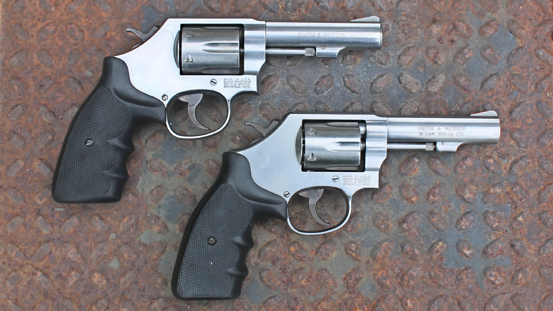 Smith & Wesson stainless steel model 64 revolvers right-side view shown on rusty treadplate with black rubber grips stocks