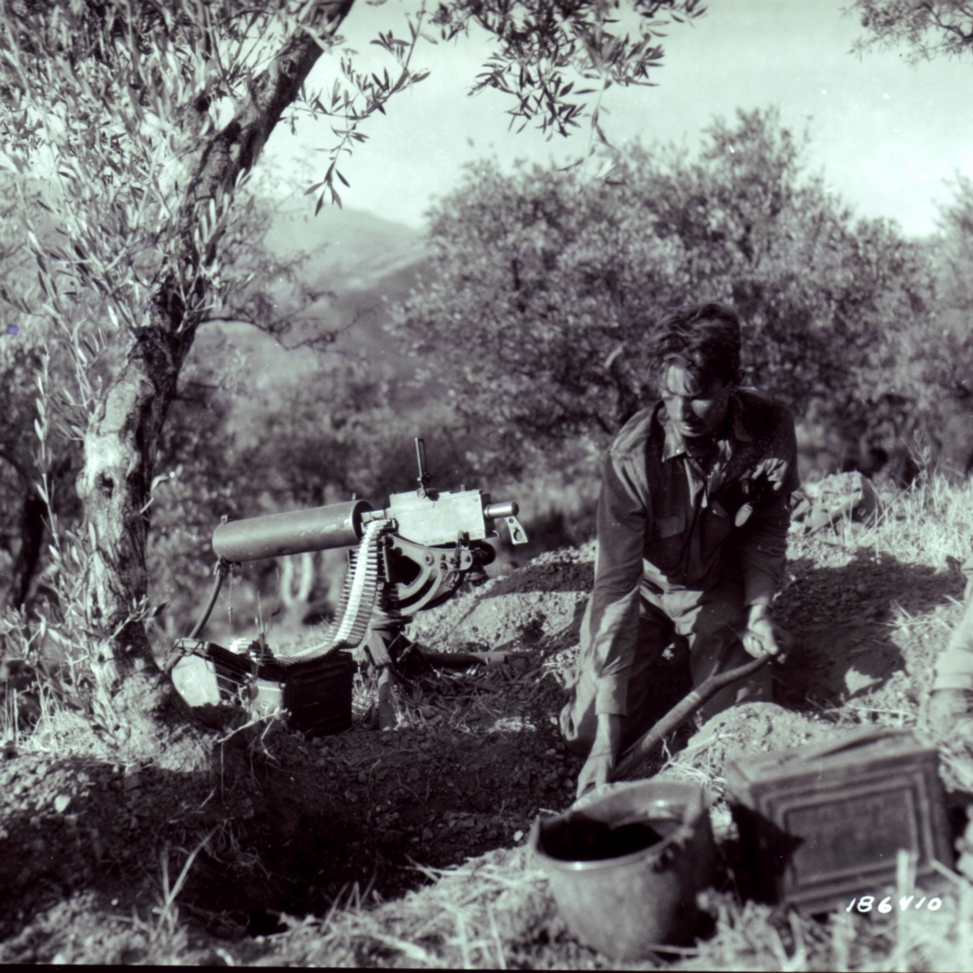 13)	Preparing for a German counterattack during Patton’s drive to Messina:  this machine gunner of the 30th Infantry Regiment scrapes out a hasty firing position for his Browning .30 caliber M1917 water-cooled MG.  NARA
