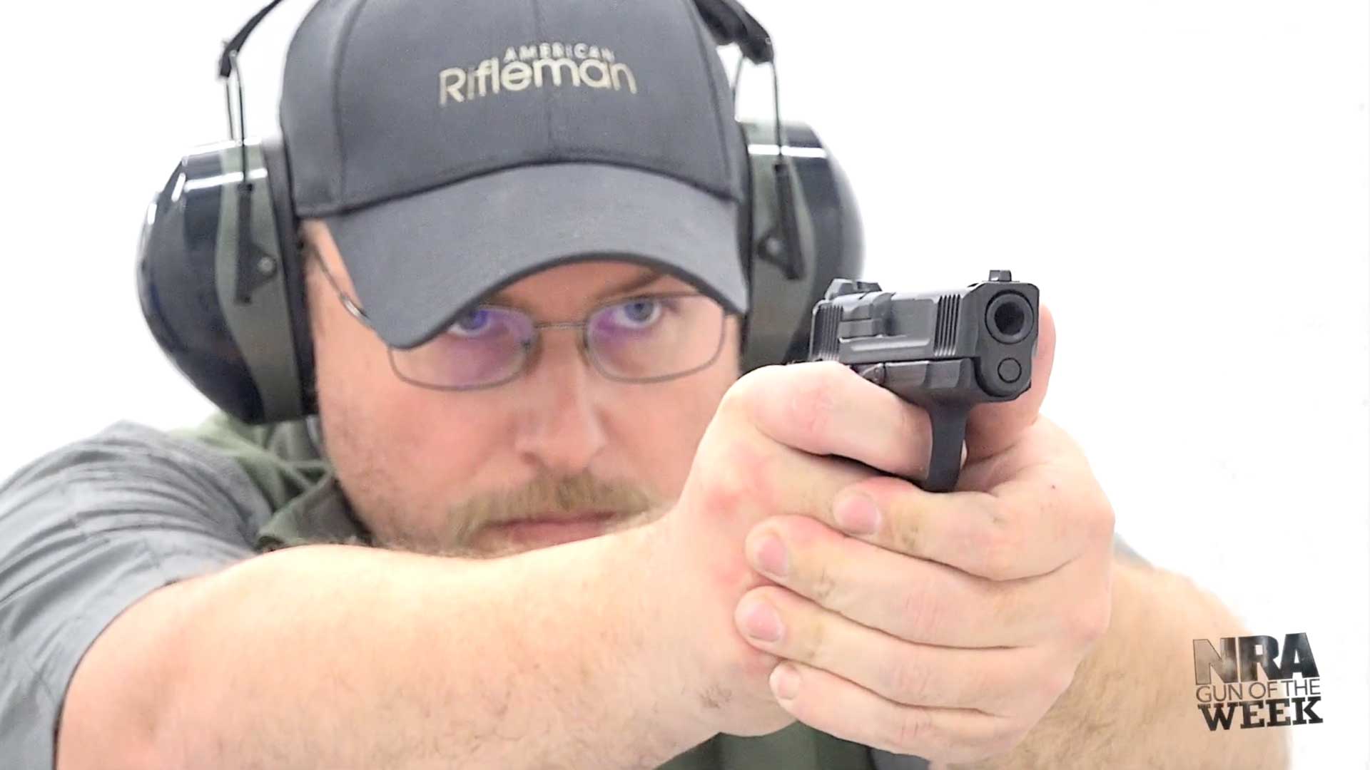 Man with handgun pistol wearing ballcap earmuffs glasses at white shooting range shooting pistol handgun smith&wesson csx hammer-fired semi-automatic nra gun of the week