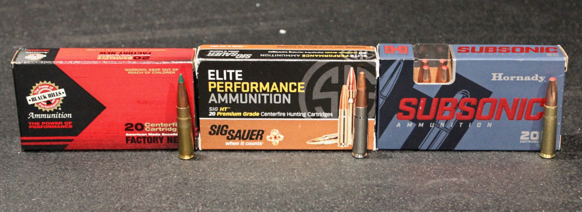 three boxes of .300 blackout ammunition in a row with cartridges standing in front for example black hills sig sauer hornady