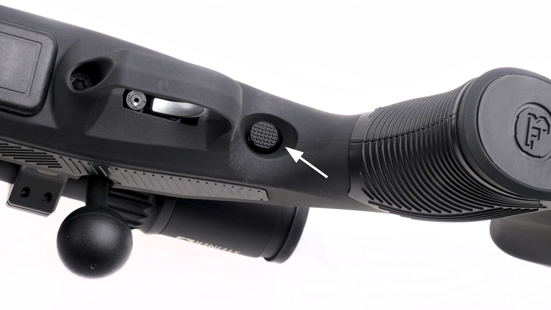 CZ 600 Alpha bolt-action rifle underside view of stock trigger guard and safety button with arrow highlighting location of the textured round safety