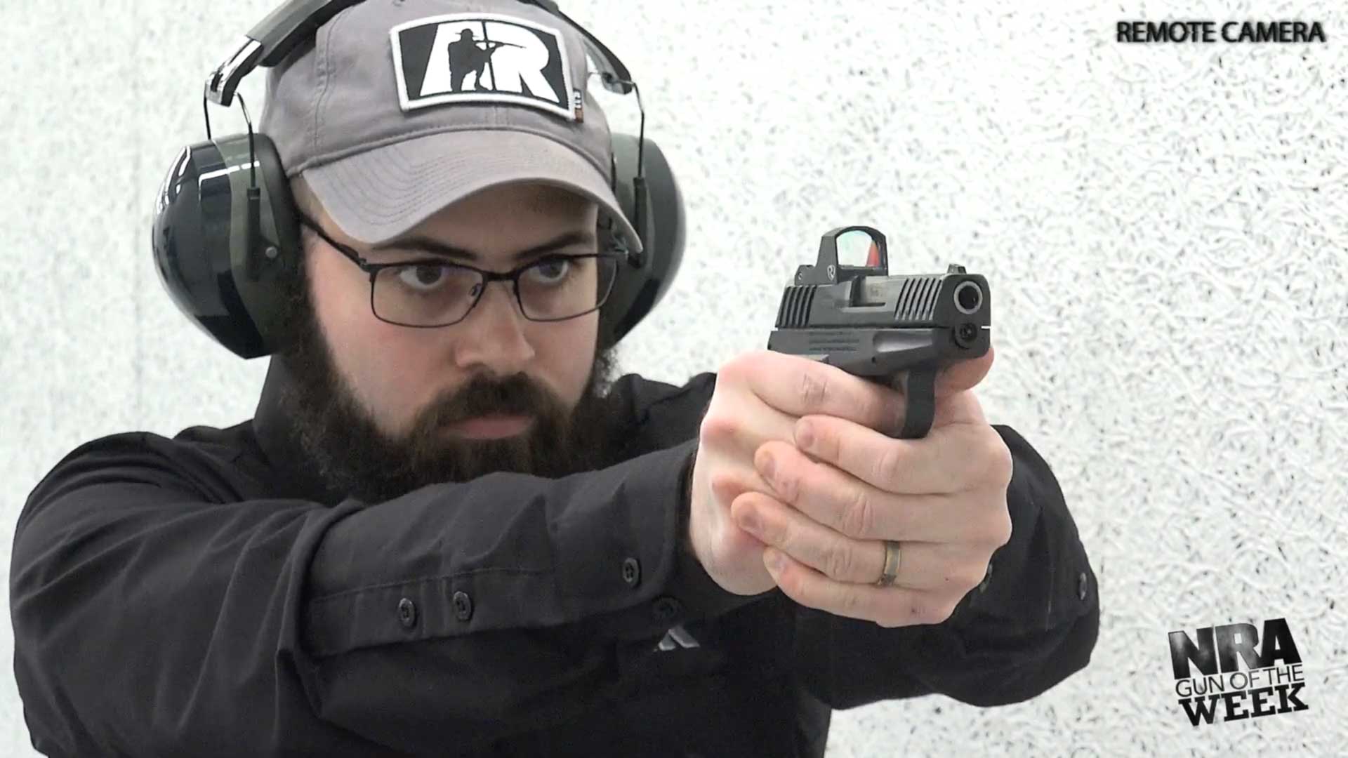 man wearing black shirt ballcap hat glasses earmuffs shooting gun pistol black handgun
