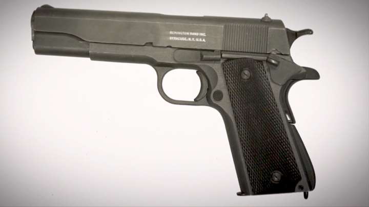 Left-side view of Remington Rand M1911A1 pistol on white background and highlight of Syracuse, N.Y. stamping on the gun&#x27;s slide.