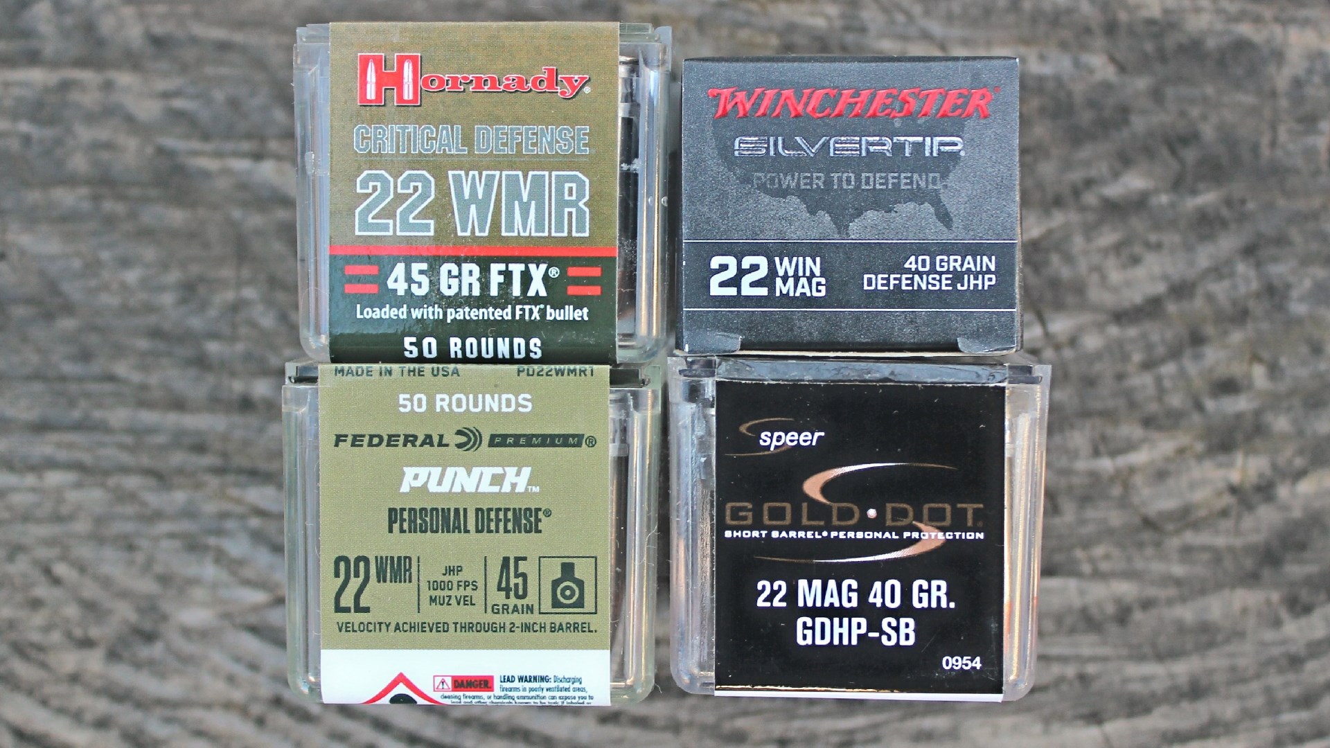 four ammunition boxes comparisons brands hornady winchester federal speer .22 WMR .22 MAG shown on log