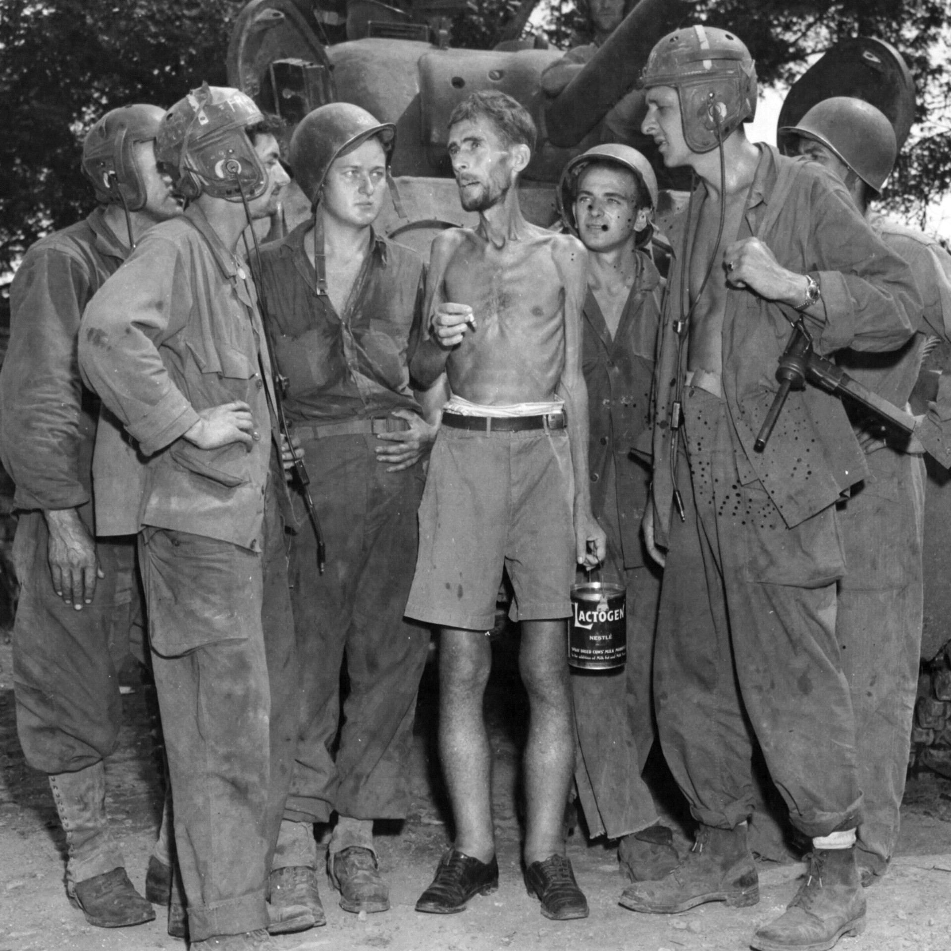 A US Army tanker with a M3 “Grease Gun” SMG, talking to a newly released prisoner from the Santo Thomas camp near Manila. February 1945.