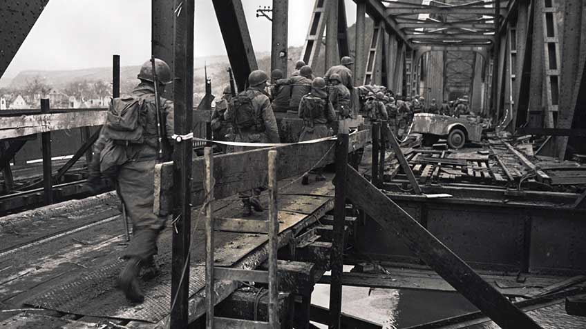 US infantrymen cross the Rhine via Ludendorff railroad bridge shortly after its capture.  The GI at the rear of the column carries a Browning Automatic Rifle.