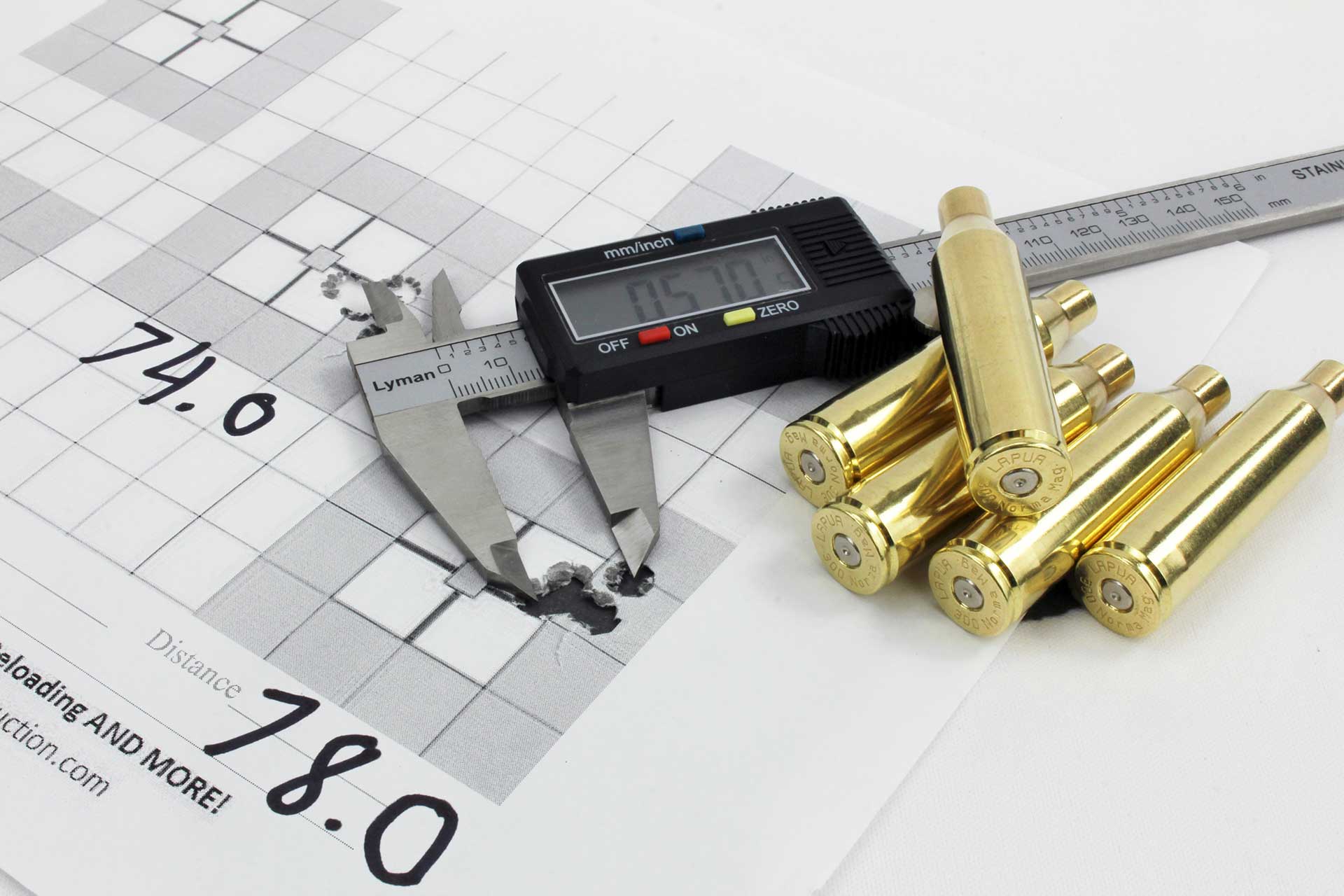 A set of digital calipers measuring an accurate shot group of nearly half an inch next to a group of bright, shiny, once-fired brass cartridge cases