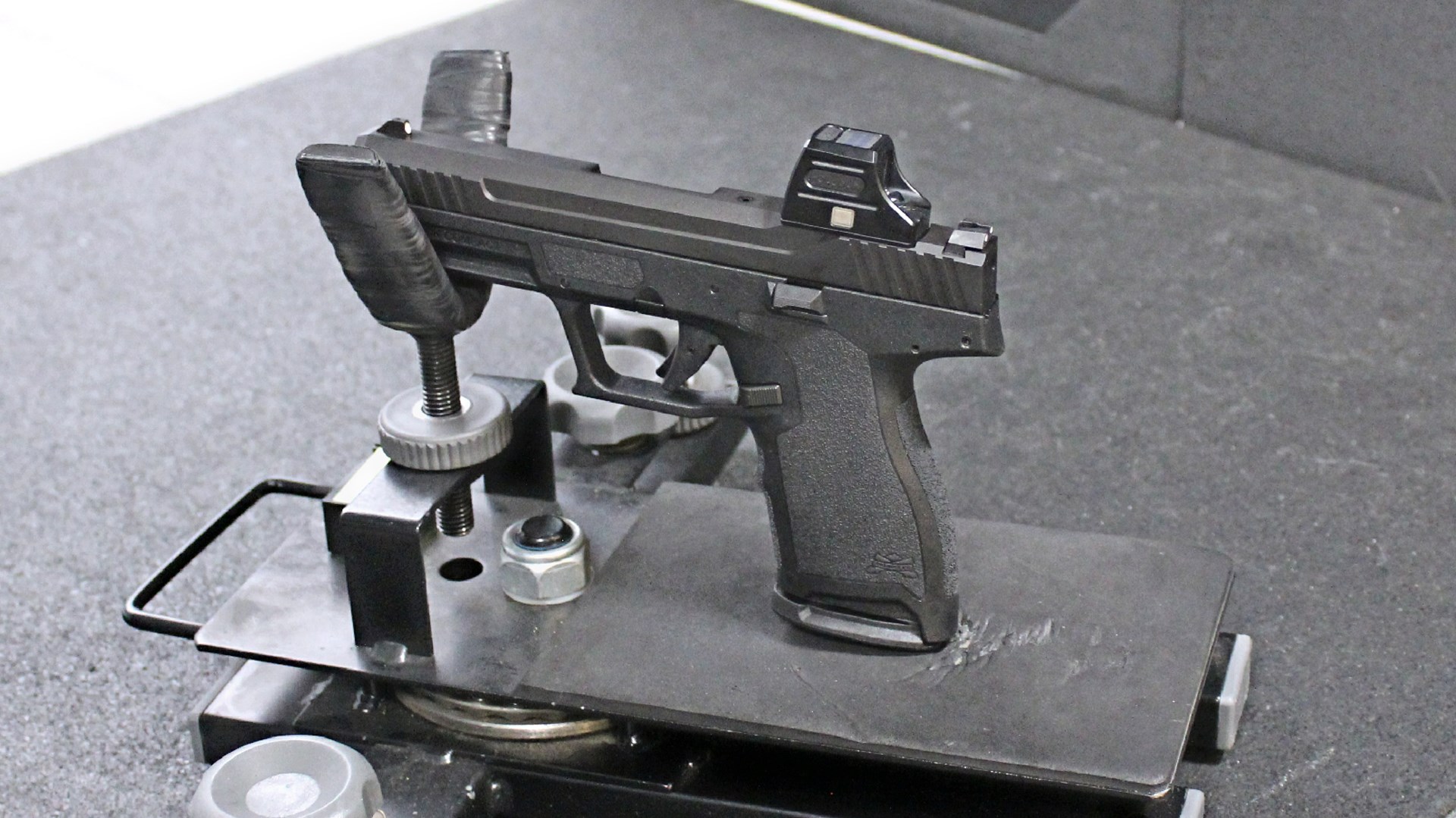 Palmetto State Armory 5.7 Rock Compact pistol in cradle on shooting range shown with holosun red-dot optic attached