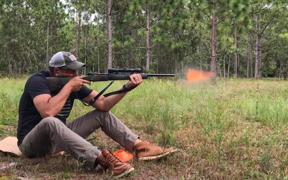 shooter sitting in the woods with rifle