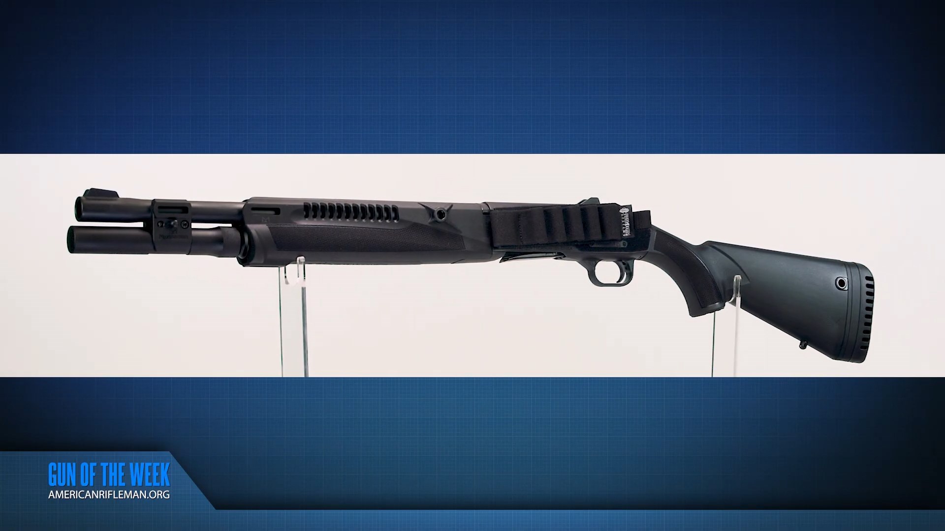 GUN OF THE WEEK Mossberg 940 Pro Tactical SPX left-side view black semi-automatic shotgun on clear acrylic stand blue and white background