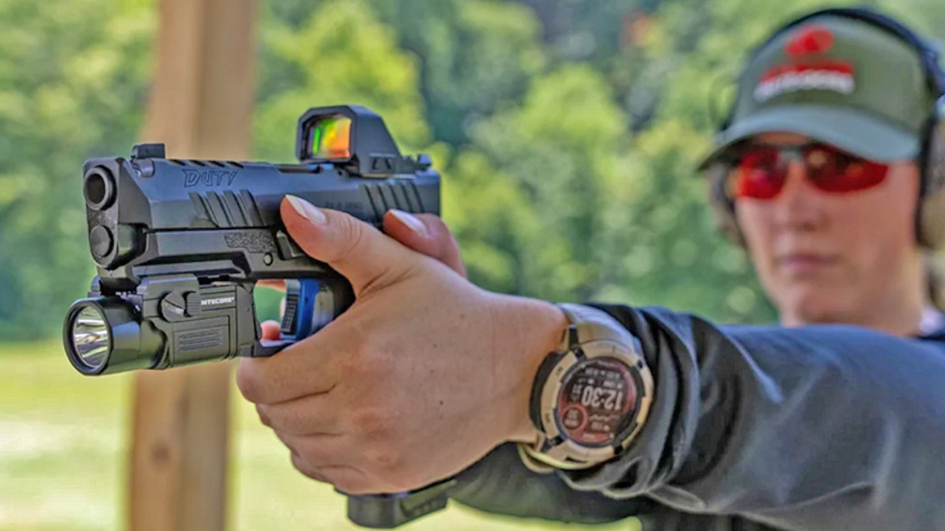 Man aiming a Tisas PX-9 Duty Comp pistol equipped with a red-dot optic and a weaponlight.