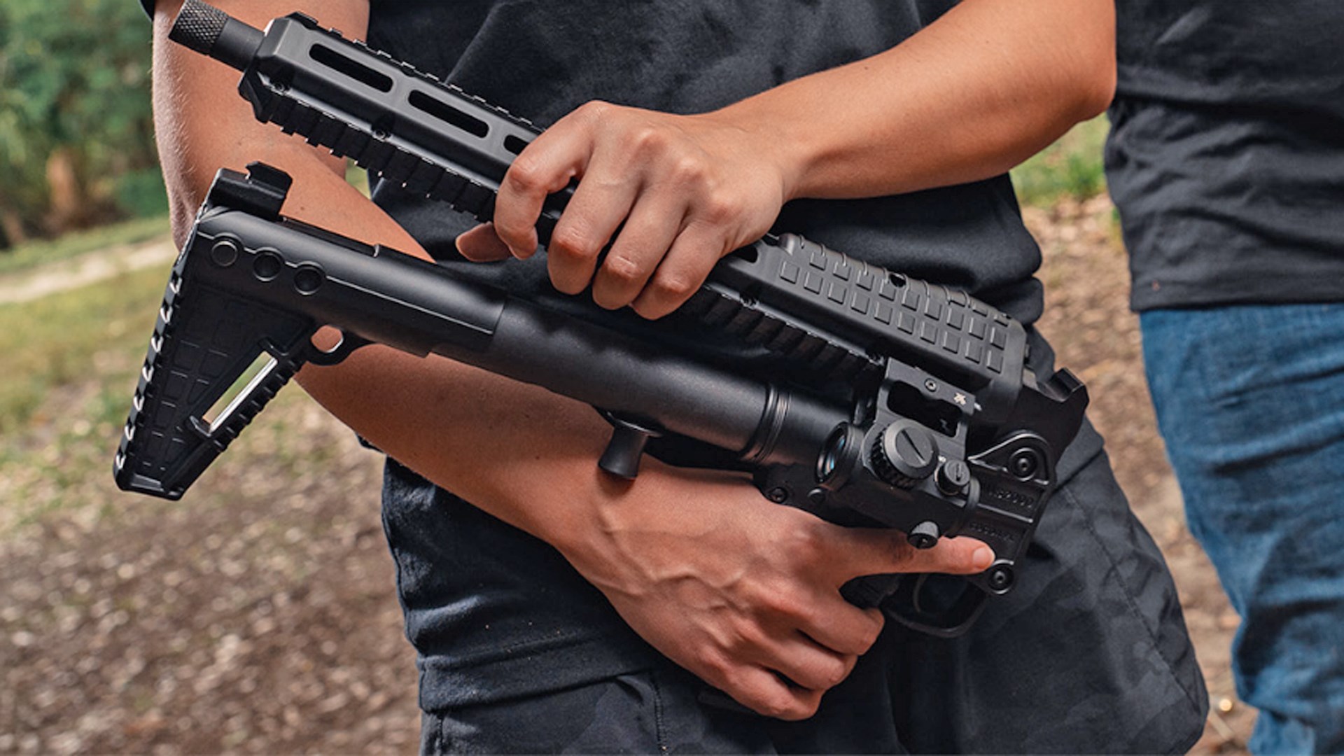 Man folding the KelTec SUB2000 10 mm Auto on an outdoor range.
