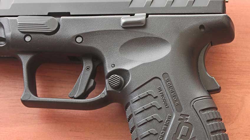 plastic handgun frame closeup trigger magazine release metal slide all black
