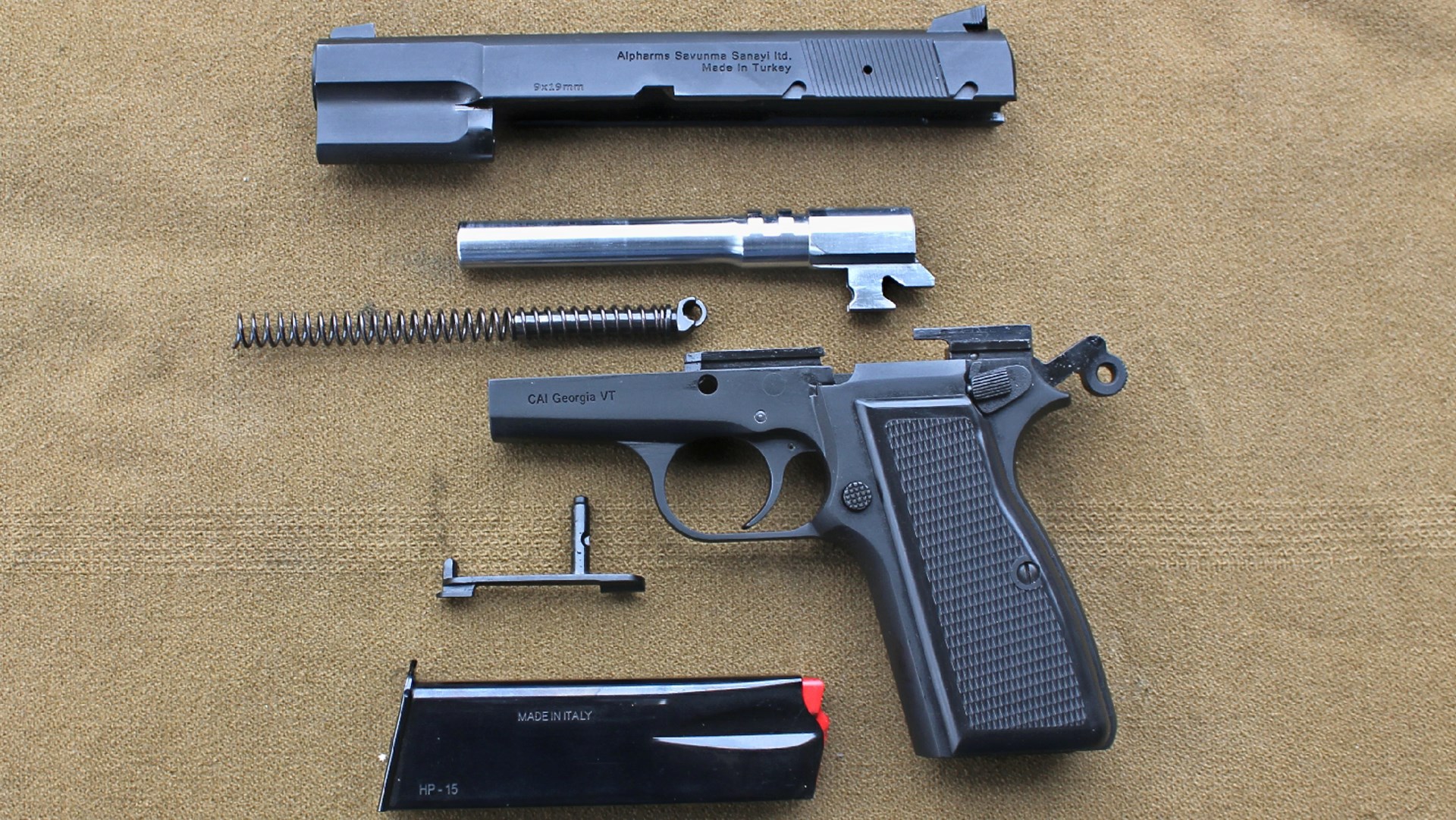 Century Arms Centurion 14 pistol left-side view exploded parts arrangement slide barrel spring frame pin magazine on brown tan soft background
