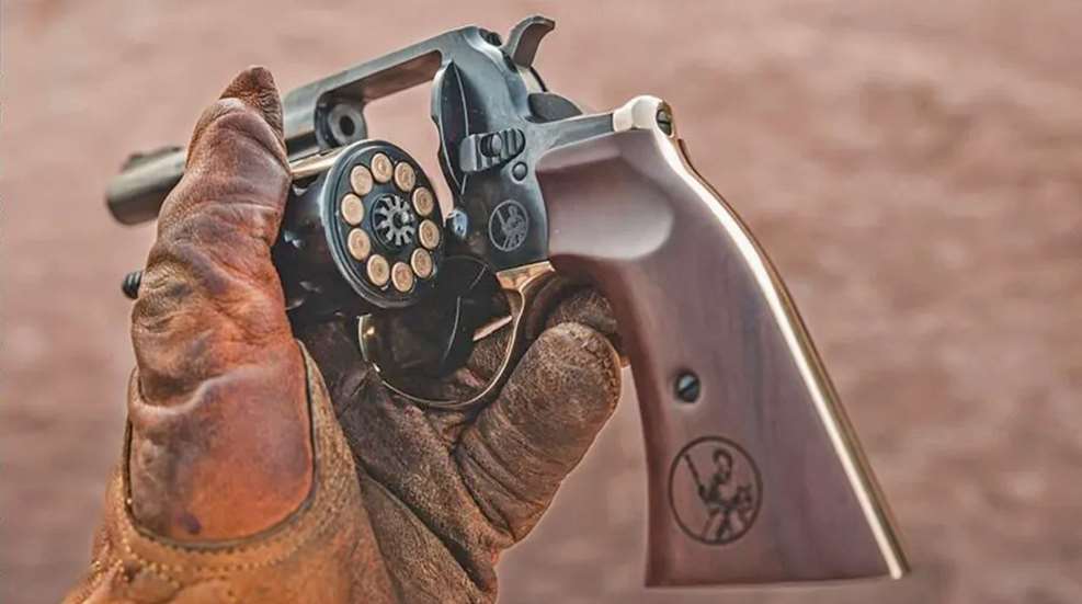A gloved hand holding a Henry Golden Boy revolver with an open cylinder.