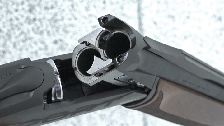 Black shotgun receiver open on gray background.