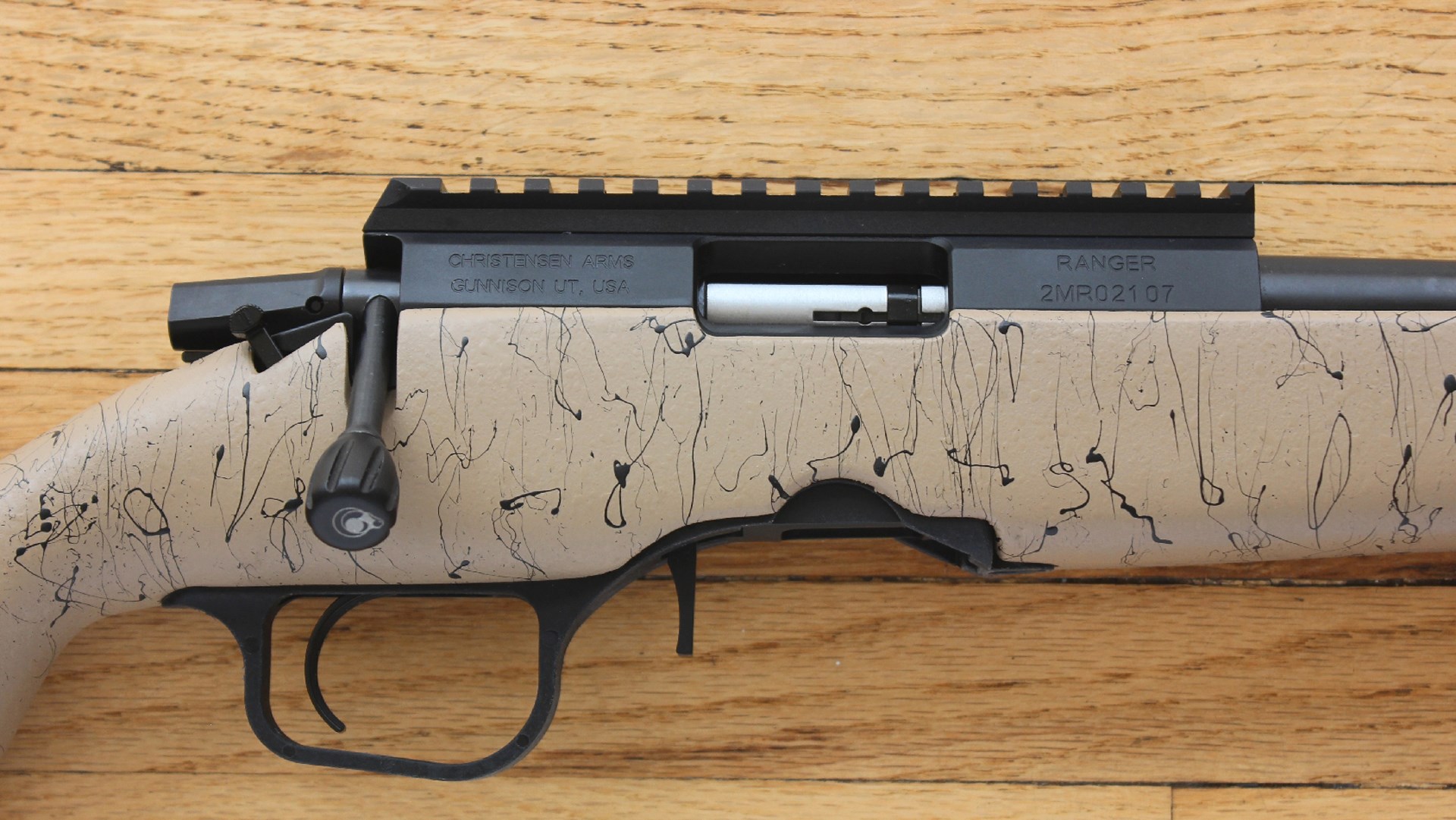 Christensen Arms Ranger bolt-action rifle FDE finish splatter texture Picatinny rail for optics detail image on wood background