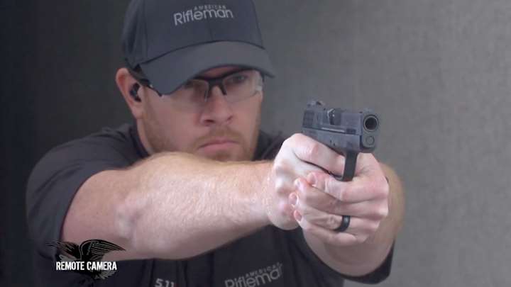 Man wearing a ballcap shooting a pistol on a shooting range.
