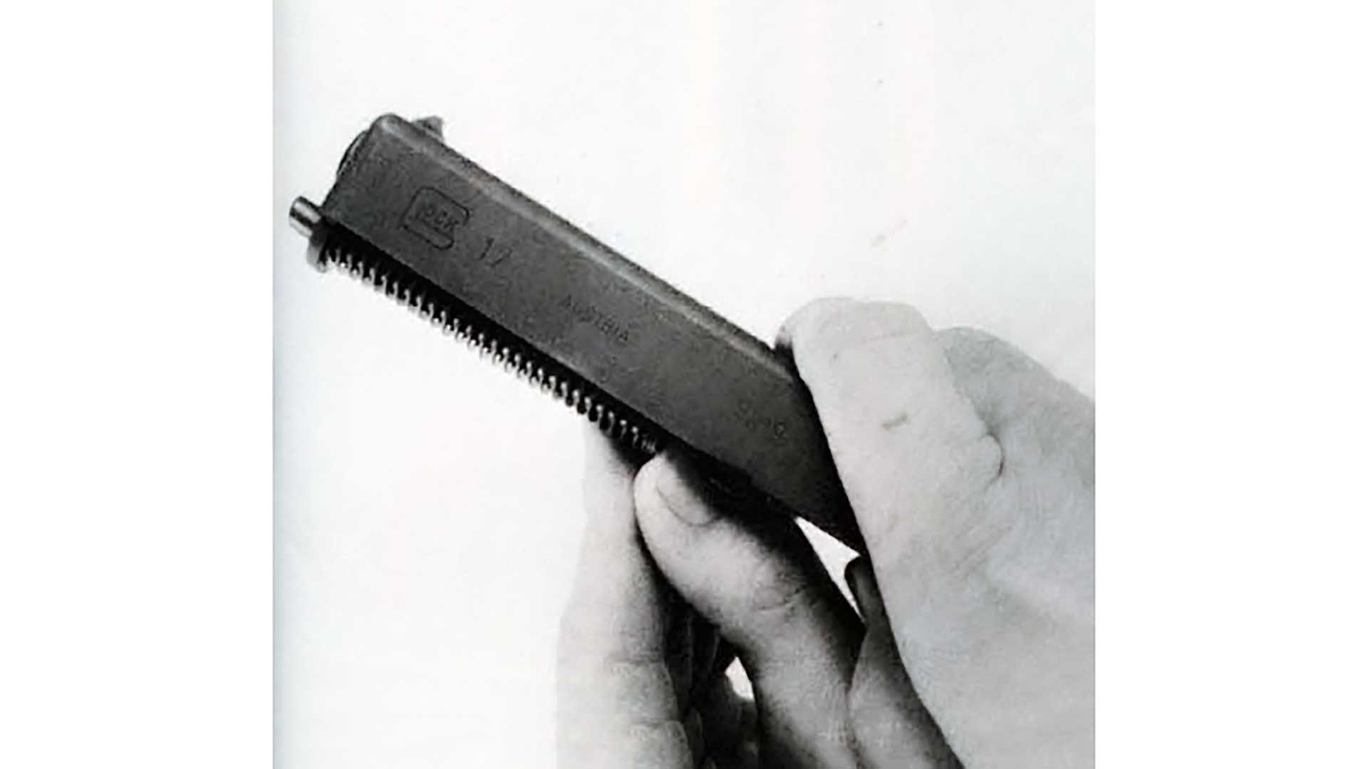 A hand removing the recoil spring from a Glock 17 slide.