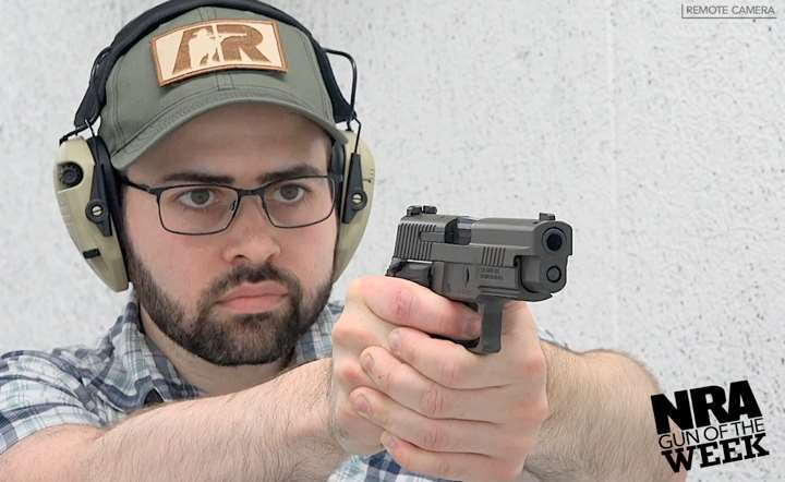 Man wearing ballcap and protective gear shooting a pistol on a shooting range.