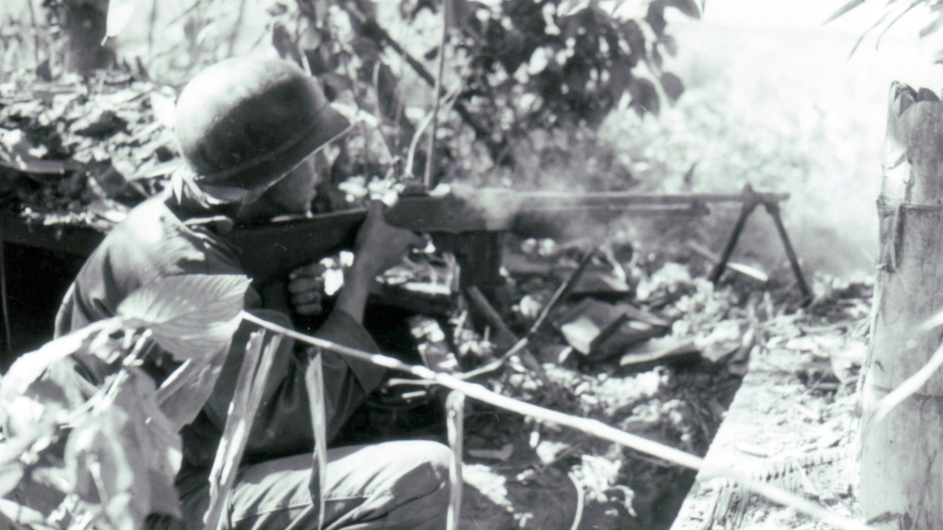 U.S. soldier gunner with BAR on bipod in the field firing from foxhole